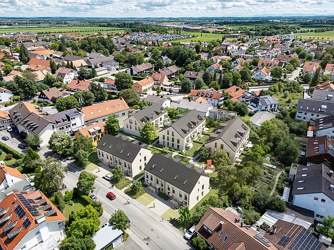 Luftbild von Aschheim bei München mit Neubauwohnungen, Kirche und Wohnsiedlung im Grünen.