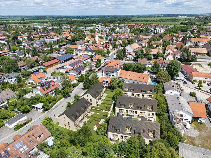 Luftbild von Aschheim bei München mit Neubauwohnungen, Kirche und Wohnsiedlung im Grünen.