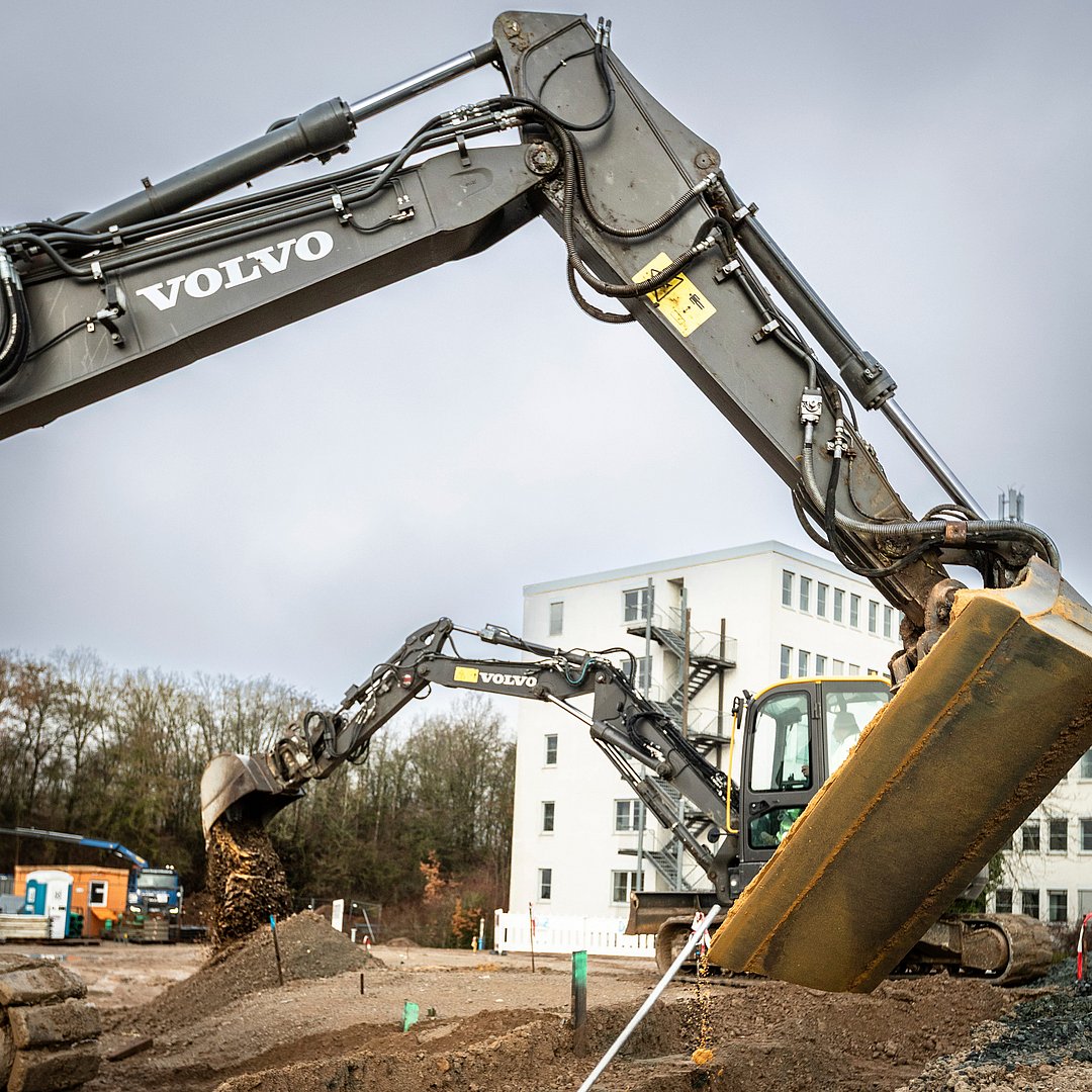 Baustellenarbeiten mit Baggern im Neubauprojekt joseph vor einem Wohngebäude 