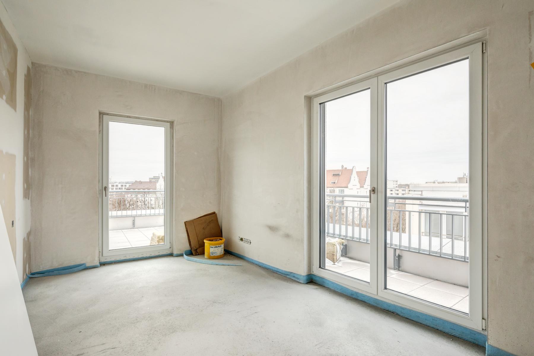 Innenausbau einer Wohnung mit Baustelleneimer, mit Blick auf den Balkon.